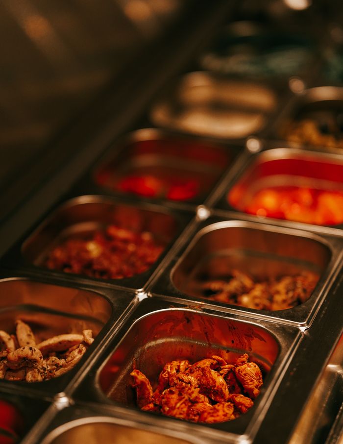 Close-up view of gourmet food selection in metal trays at a buffet, highlighting variety and choice.